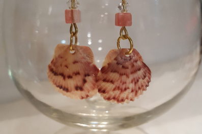 sea shell earrings hanging on rim of glass